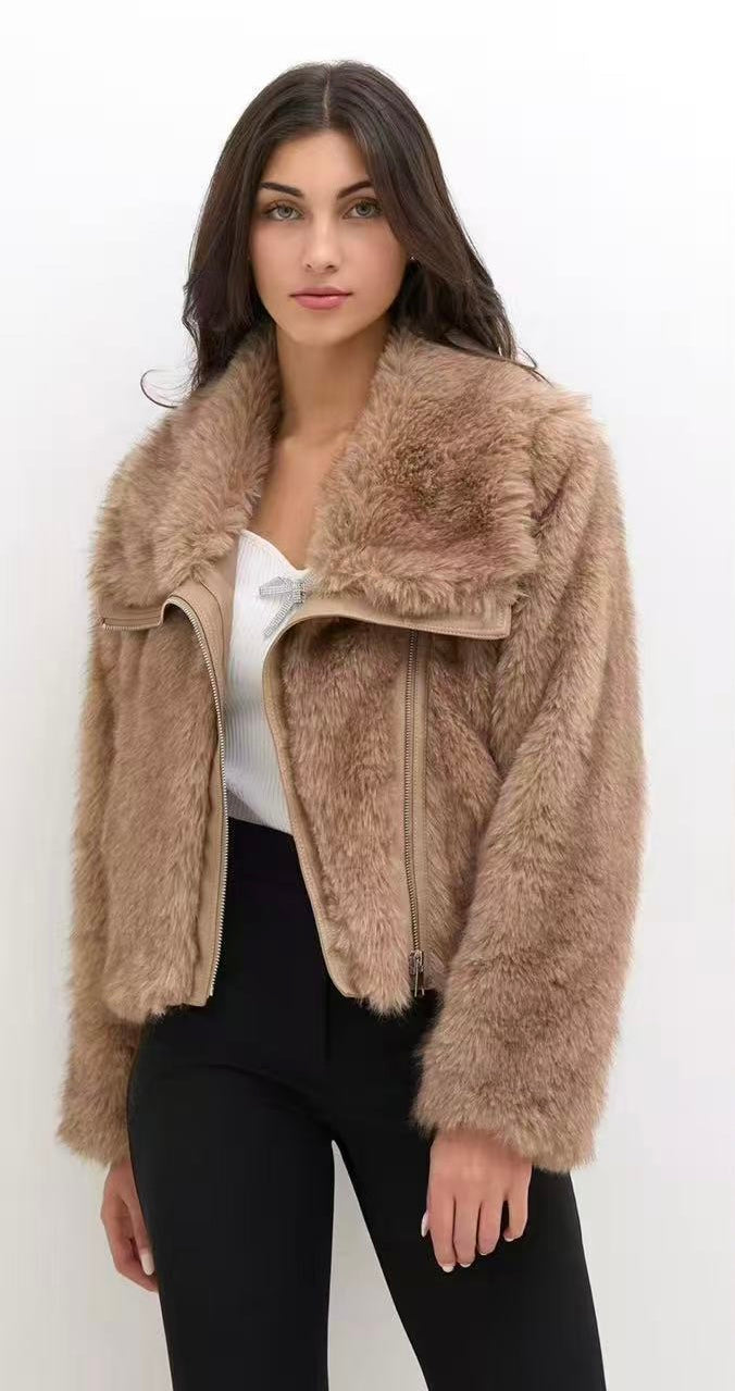 Una ragazza con capelli lunghi indossa una giacca in pelliccia camello scura, top bianco e pantaloni neri, posando per una foto di moda.