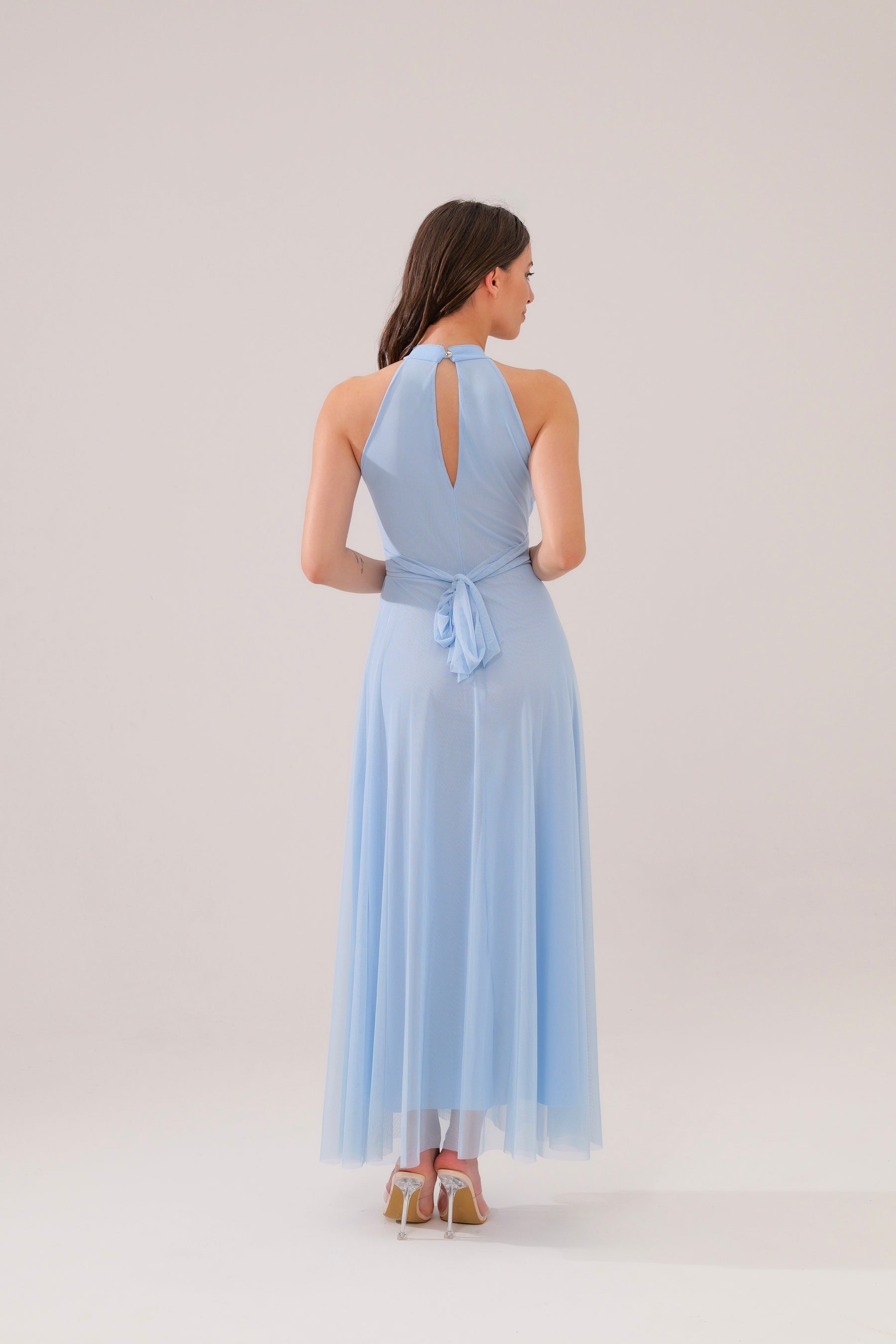 Abito azzurro elegante a colletto, modello con gonna fluida, sfondo minimalista con pianta