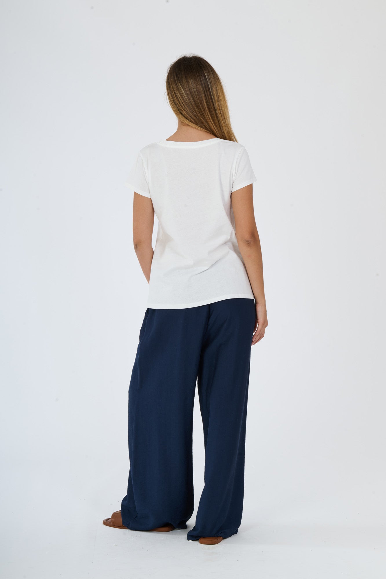 Completo bianco per l’estate: t-shirt e pantaloni larghi presentati da una ragazza