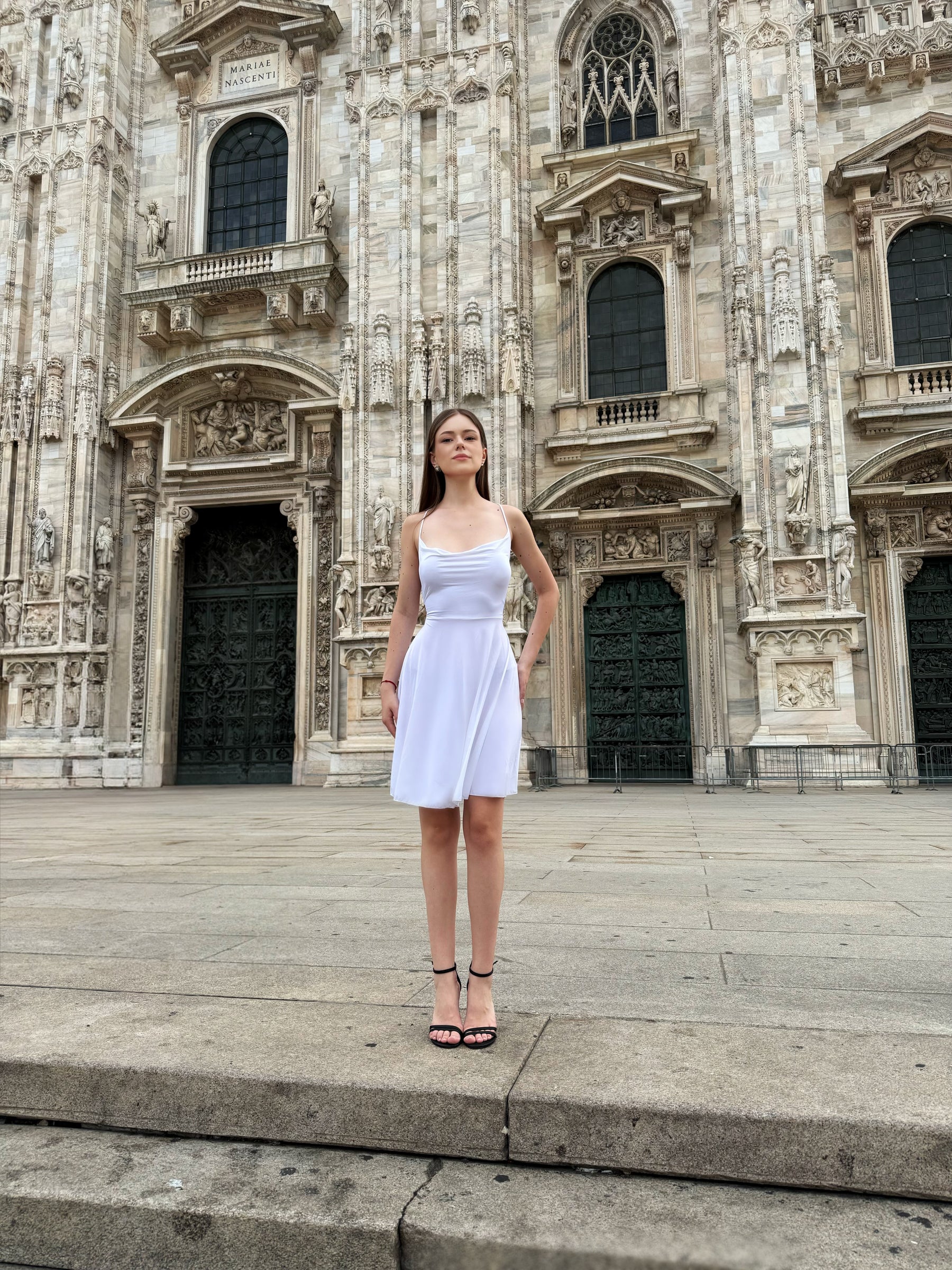Donna in abito corto bianco davanti al Duomo di Milano