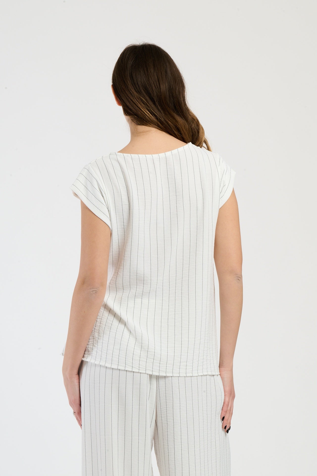 Donna in set bianco con top a nodo, combinazione impeccabile per eventi speciali.