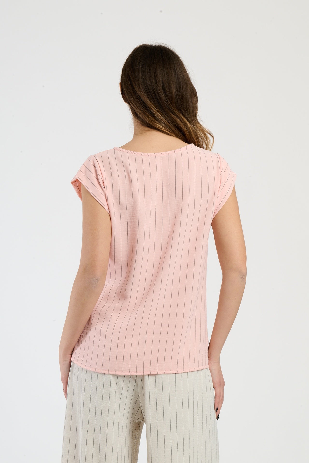 Donna in set rosa con top a nodo, combinazione accattivante per giornate estive.