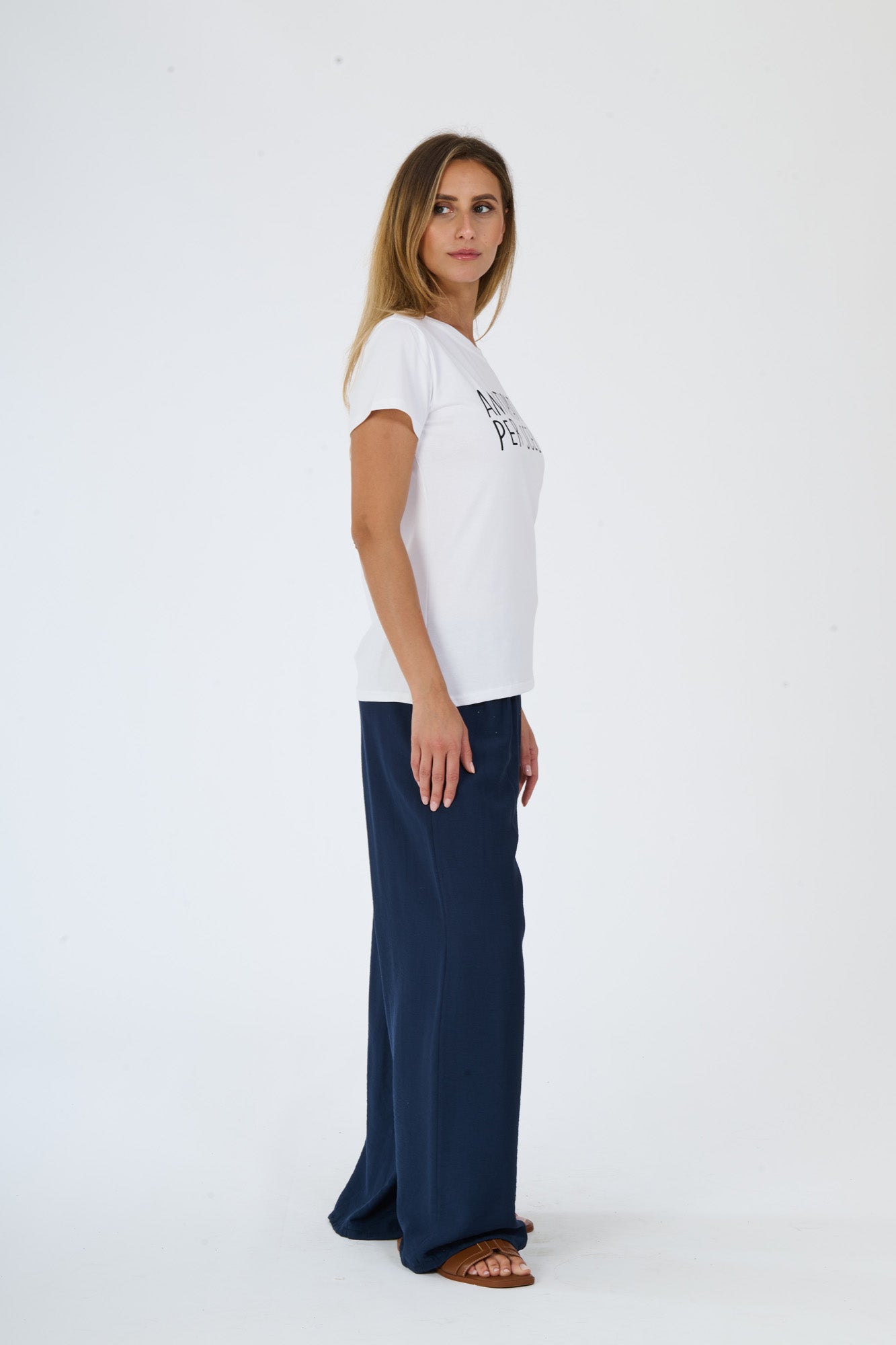 Donna indossa t-shirt bianca decorata e pantaloni scuri fluidi
