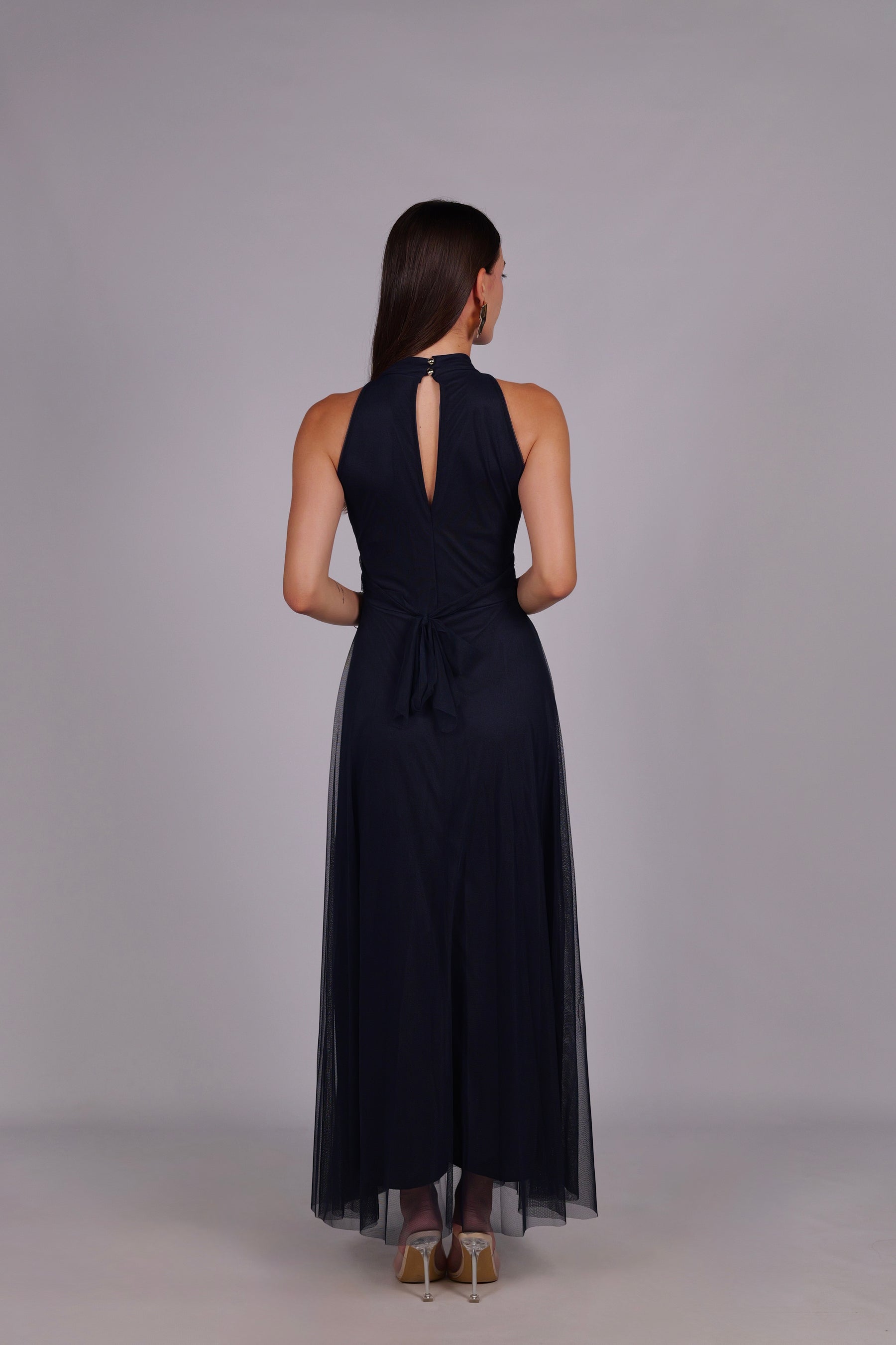 Modella con abito navy a gonna lunga, collo a imbarcatura, foulard in tulle trasparente, outfit sofisticato per eventi.