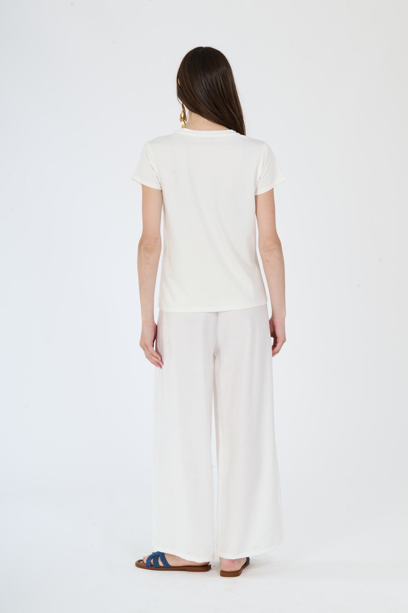 Outfit bianco semplice: t-shirt e pantaloni larghi indossati da una donna elegante