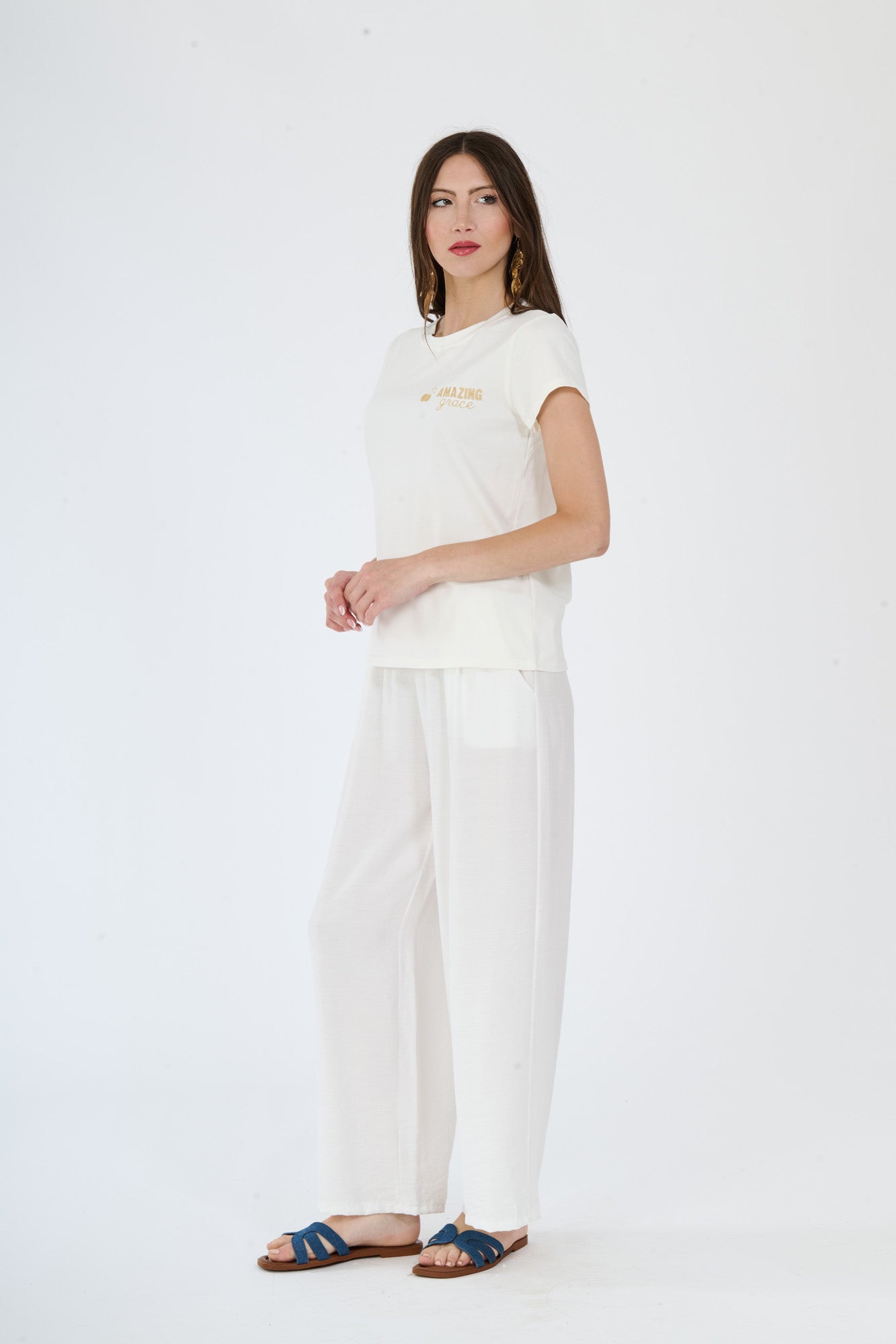 T-shirt bianca decorata e pantaloni bianchi larghi indossati da una modella