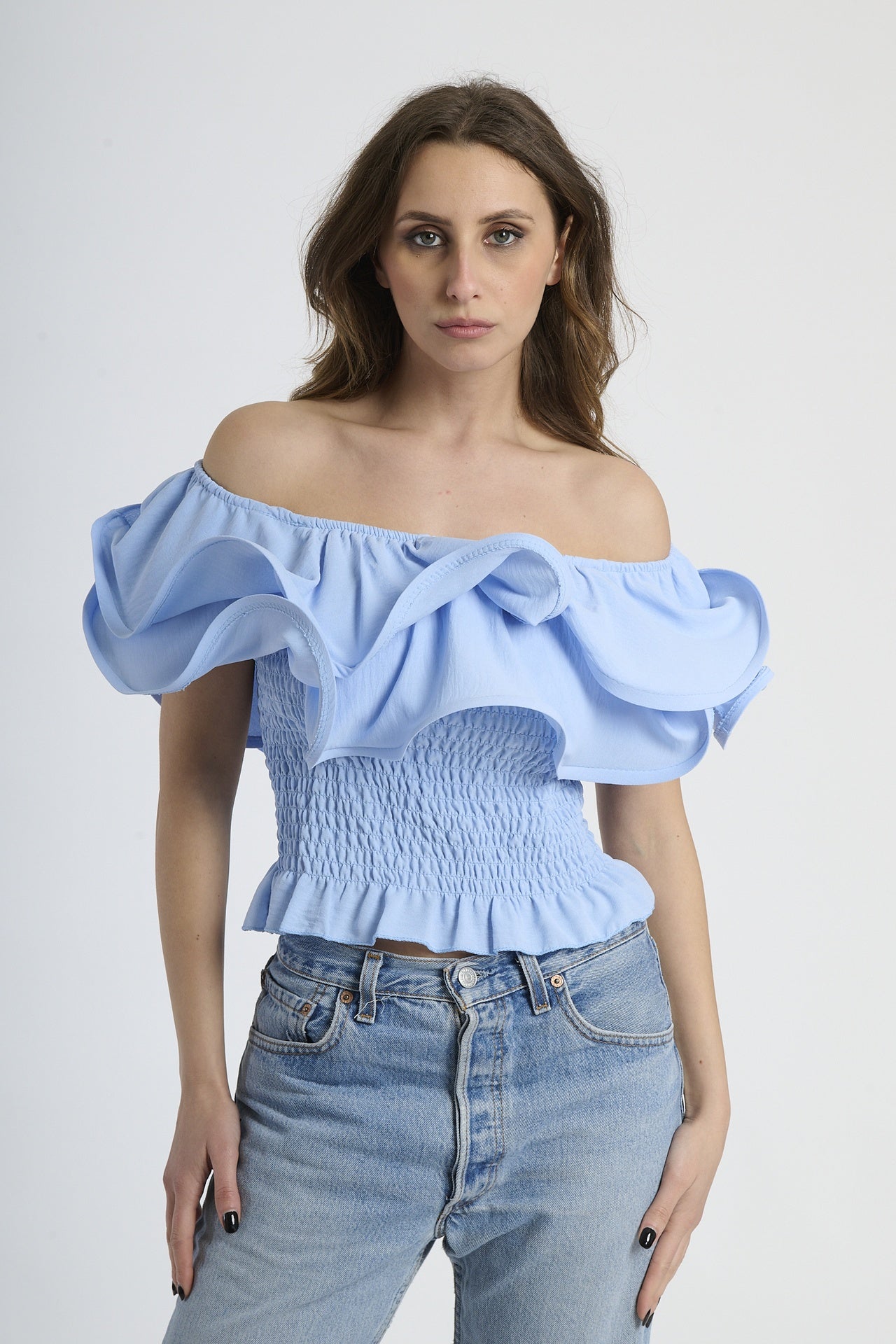 Top azzurro a spalline nude con rouches sul busto, abbinato a jeans.