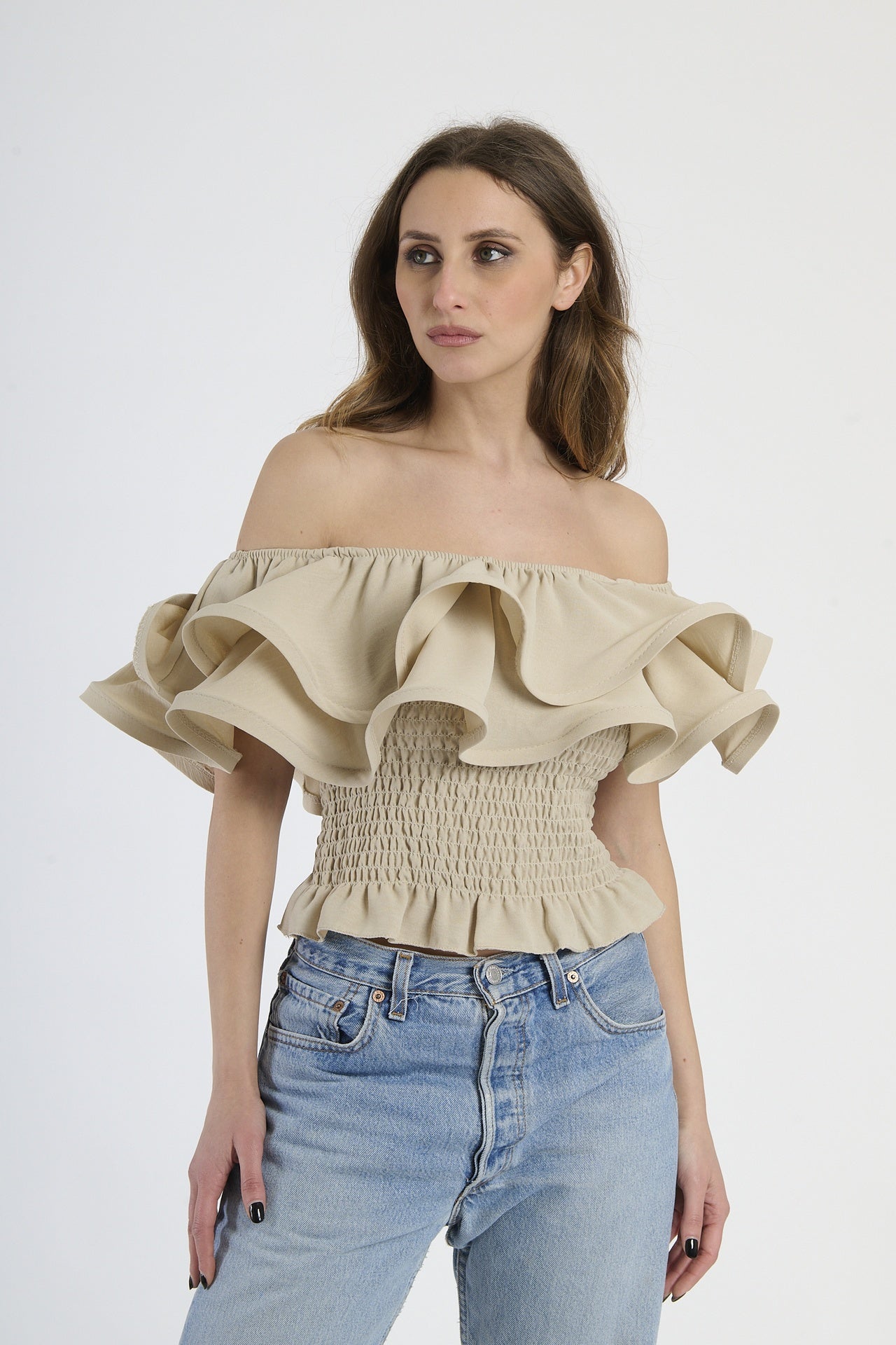 Top beige a spalline nude con rouches sul busto, abbinato a jeans.