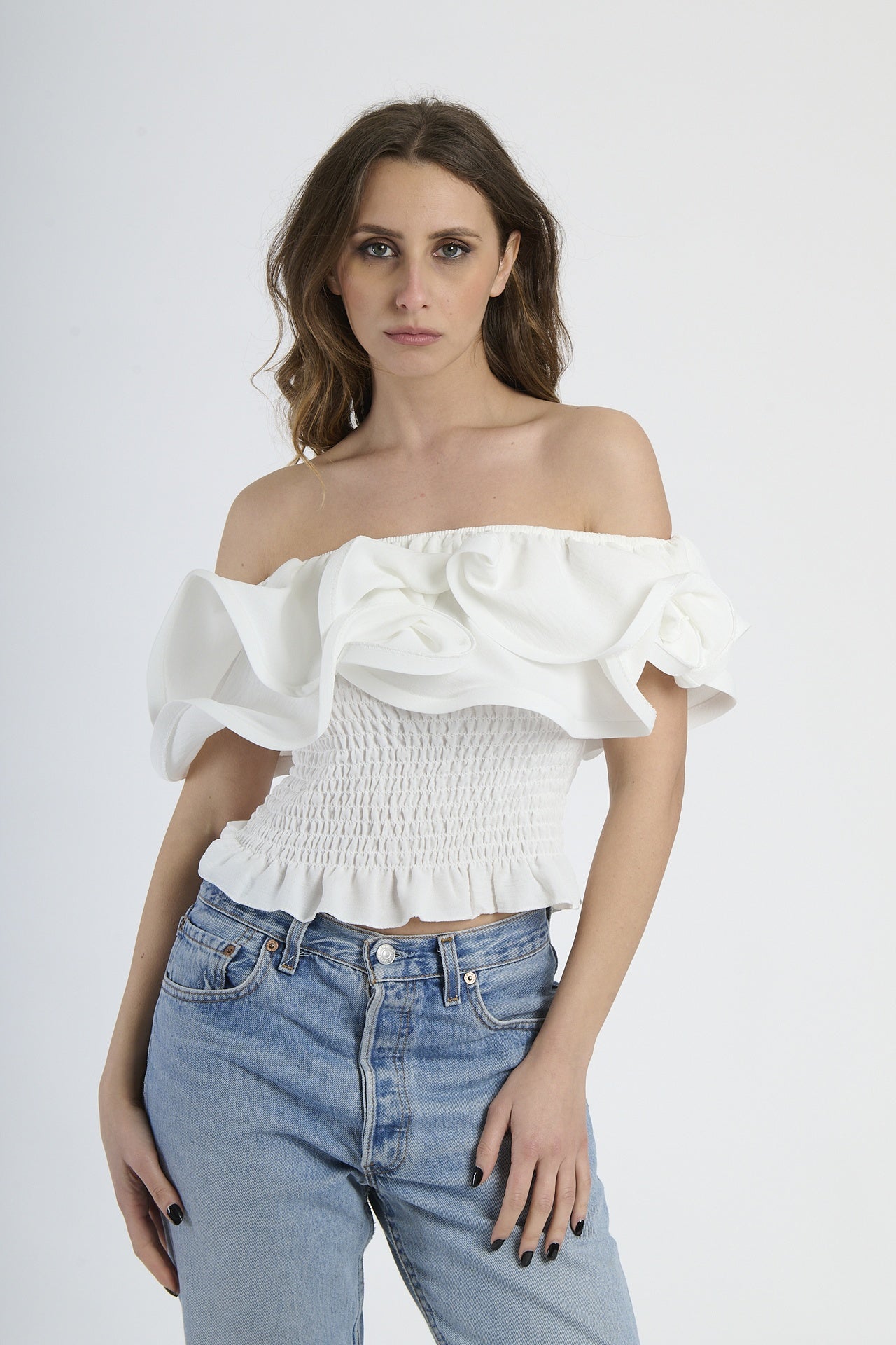 Top bianco a spalline nude con rouches sul busto, abbinato a jeans.