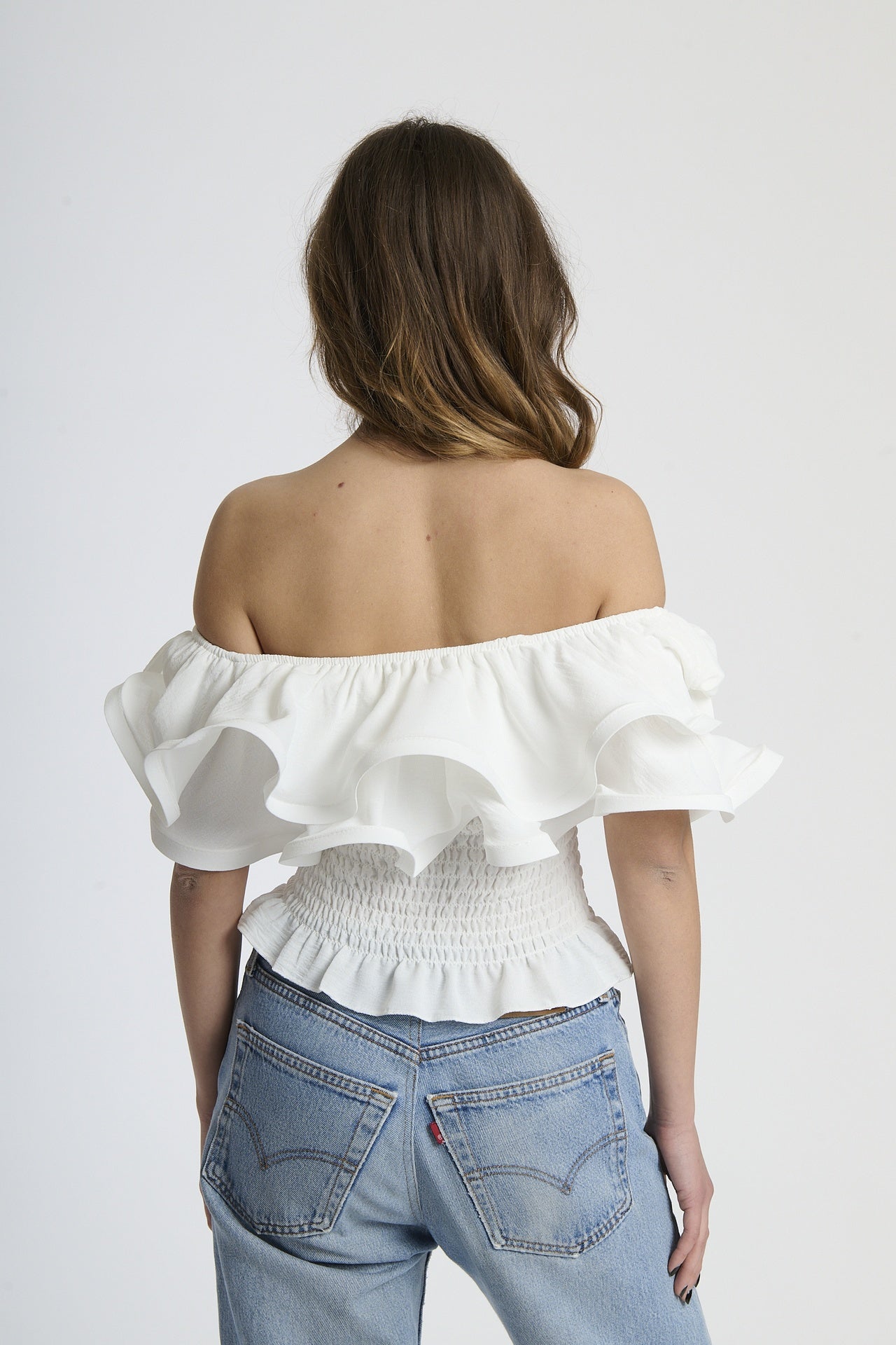 Top bianco off - shoulder con effetto smocked e rouches, stile pulito e raffinato.