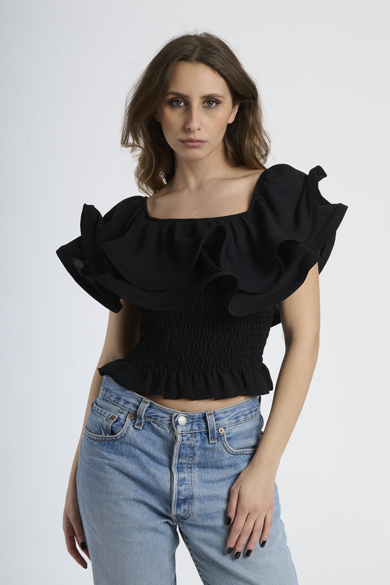Top nero a spalline nude con rouches sul busto, abbinato a jeans.