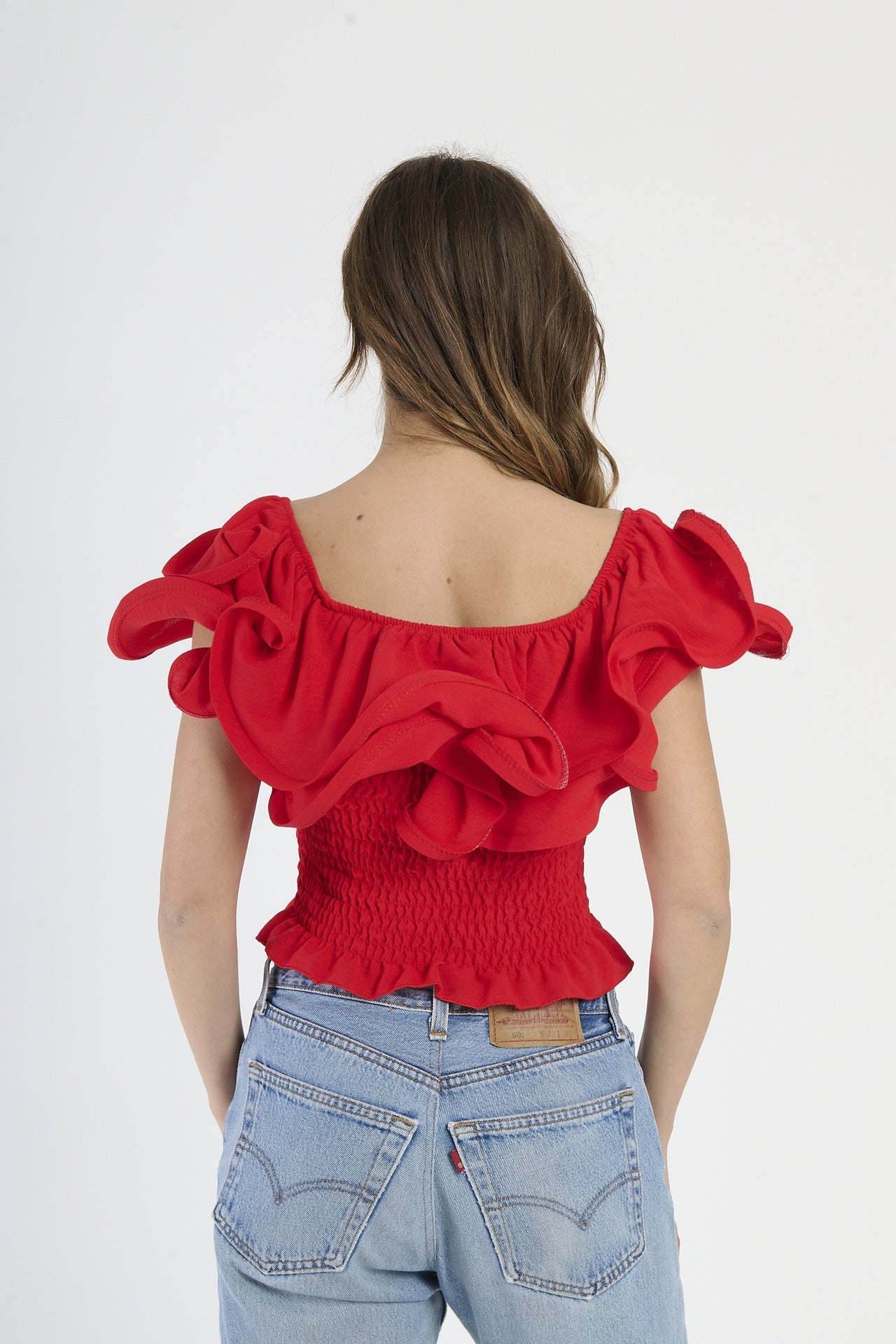 Top rosso a spalline nude, tessuto lucido con rouches sul decolleté.