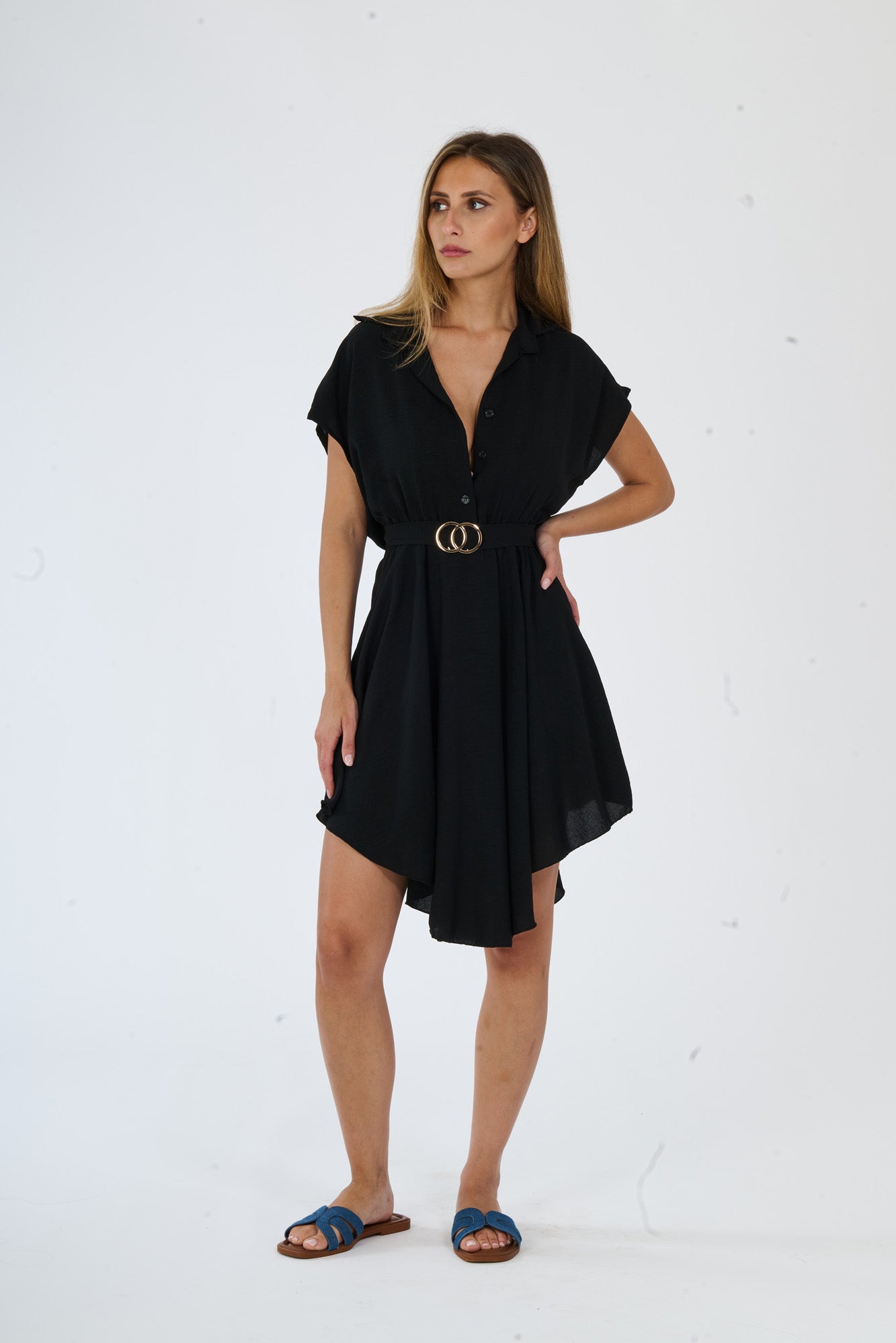 Vestito nero a camicia con taglio asimmetrico e bottoni lucidi, ideale per un look glamour ed elegante.