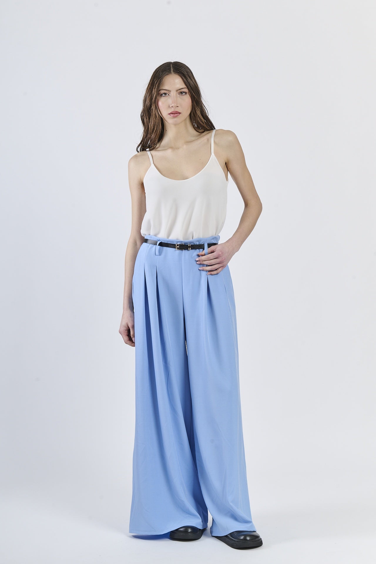 Outfit con top bianco e pantaloni azzurri ampi, cinghia nera slim