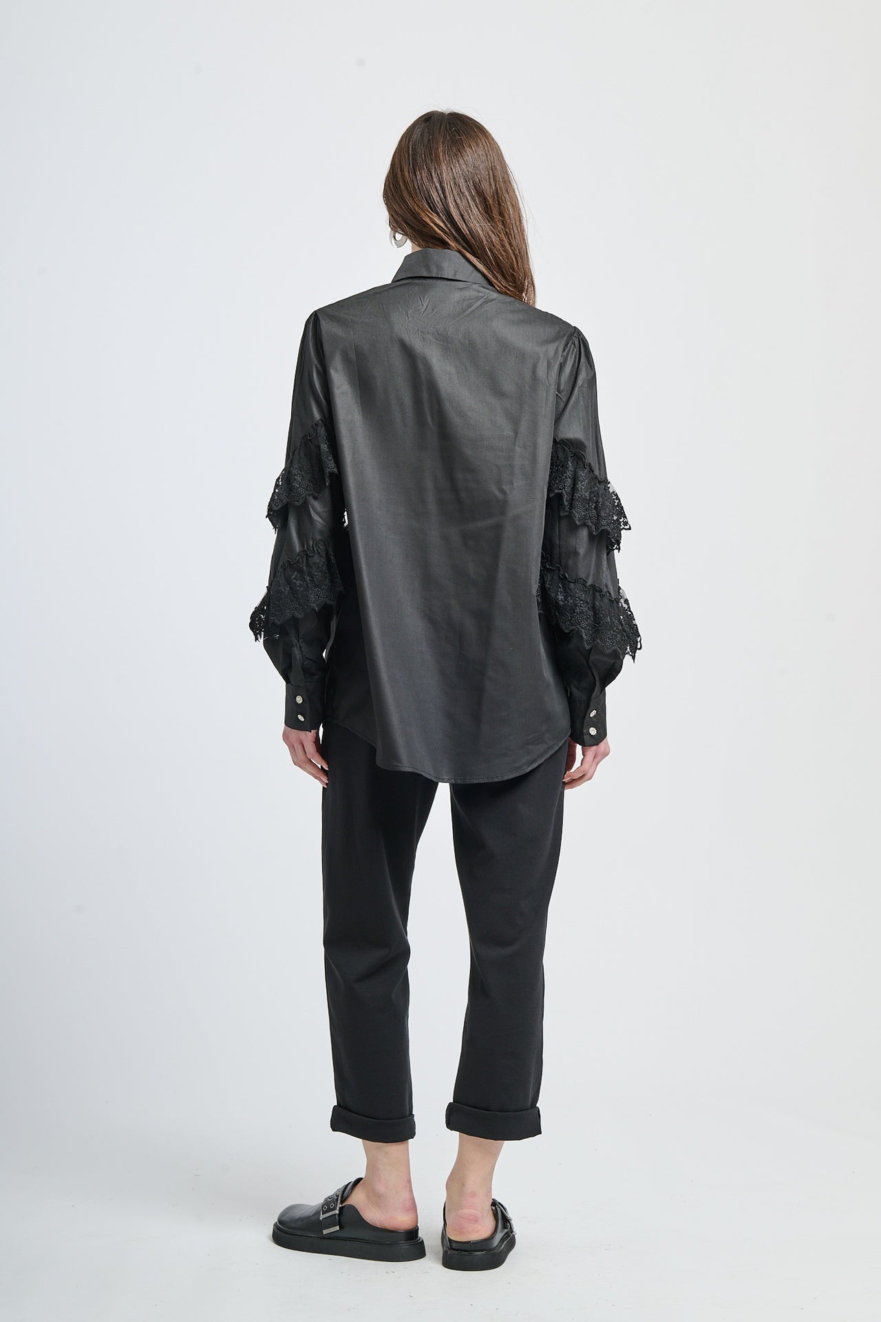 Camicia elegante in tessuto nero con incastonature di pizzo e decorazioni a chiodini.