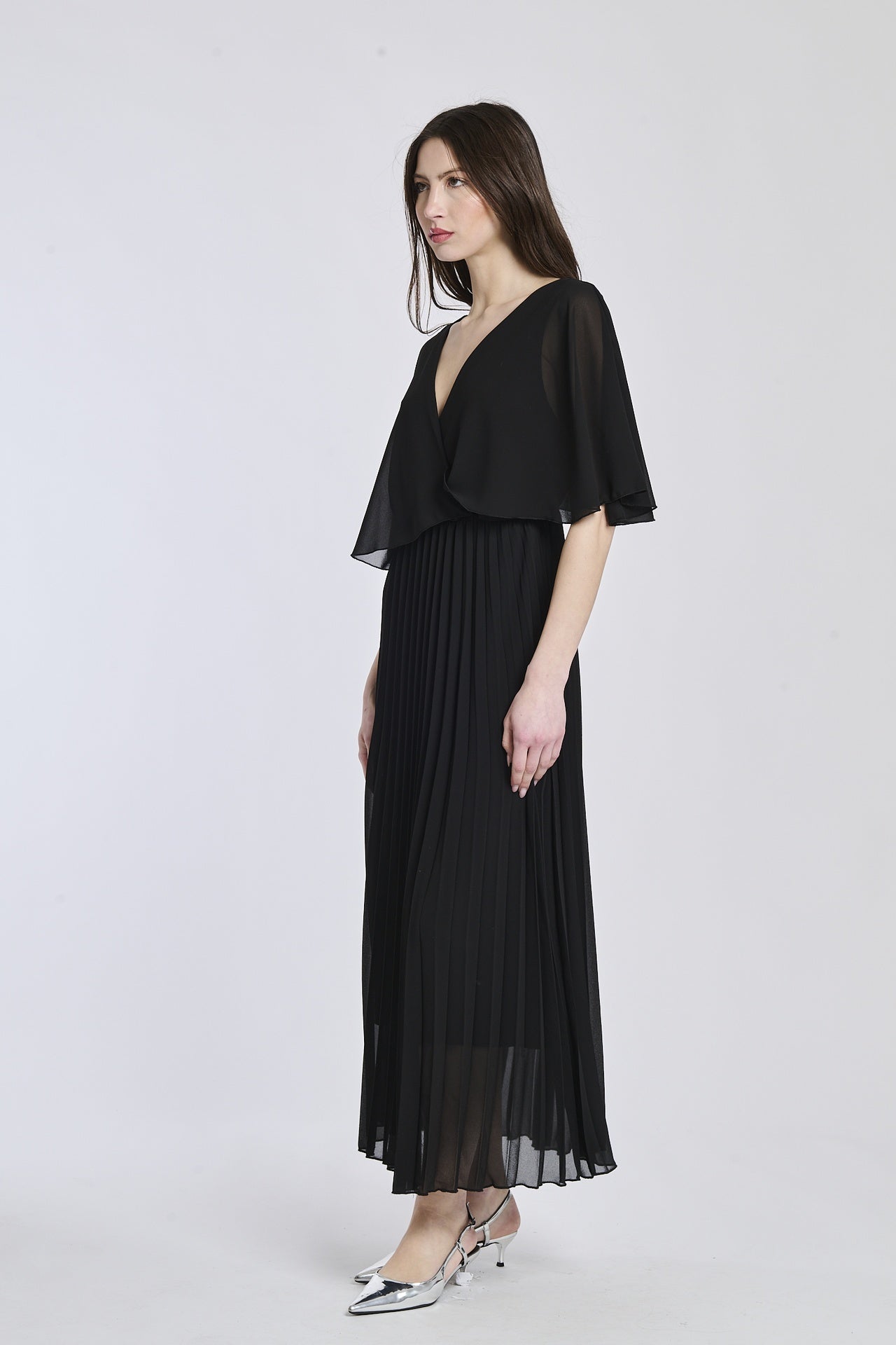 Vestito in nero profondo con dettagli di falde e maniche, offrendo un look audace e seducente.