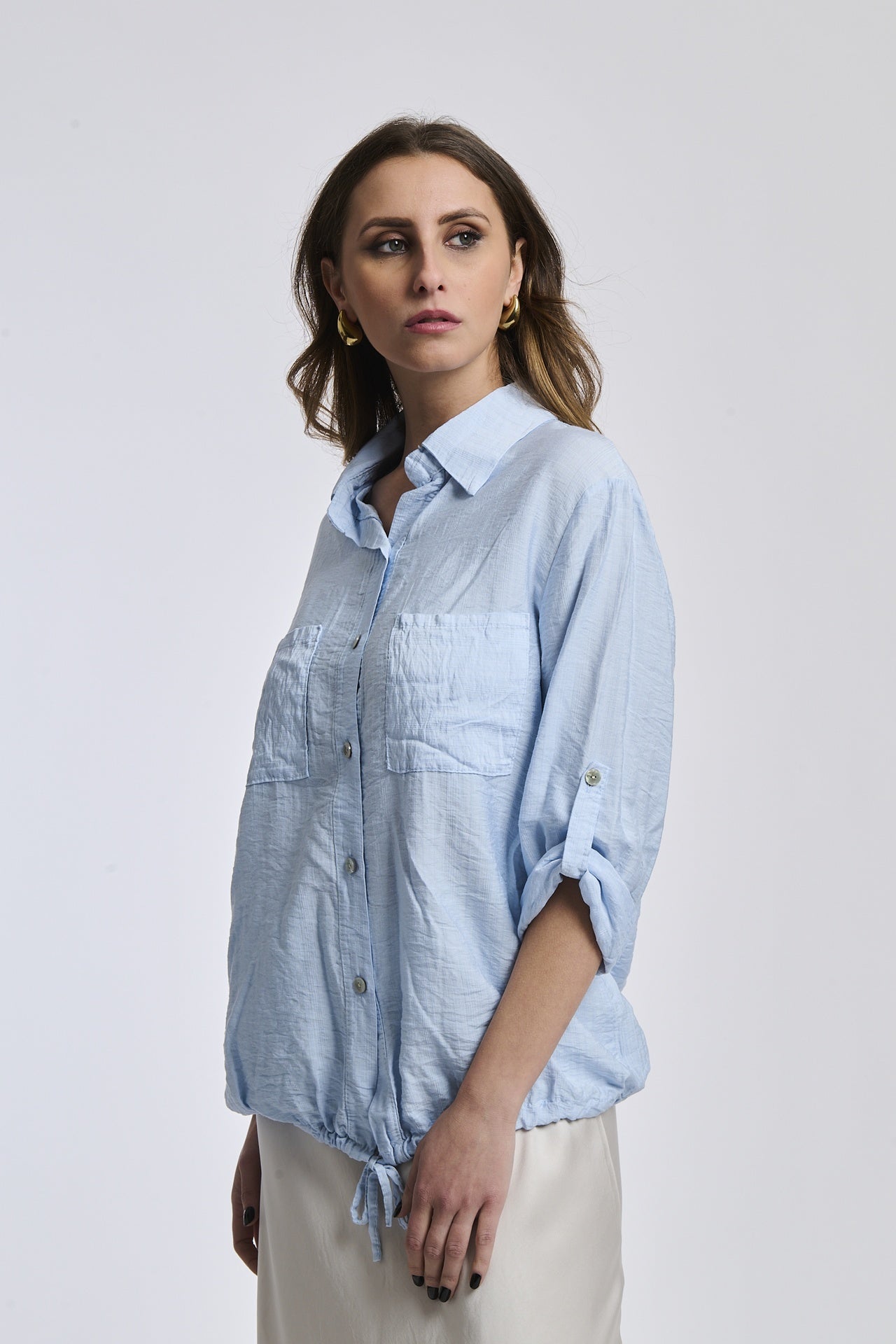 Donna indossa una camicia azzurra di cotone organico, perfetta per un look ecologico.