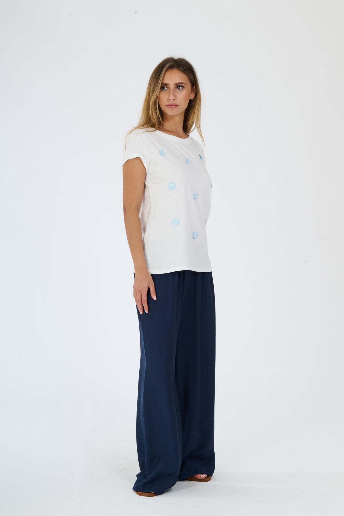 Maglietta bianca con pois azzurri abbinata a pantaloni larghi scuri,mostra uno stile fashion casual e moderno