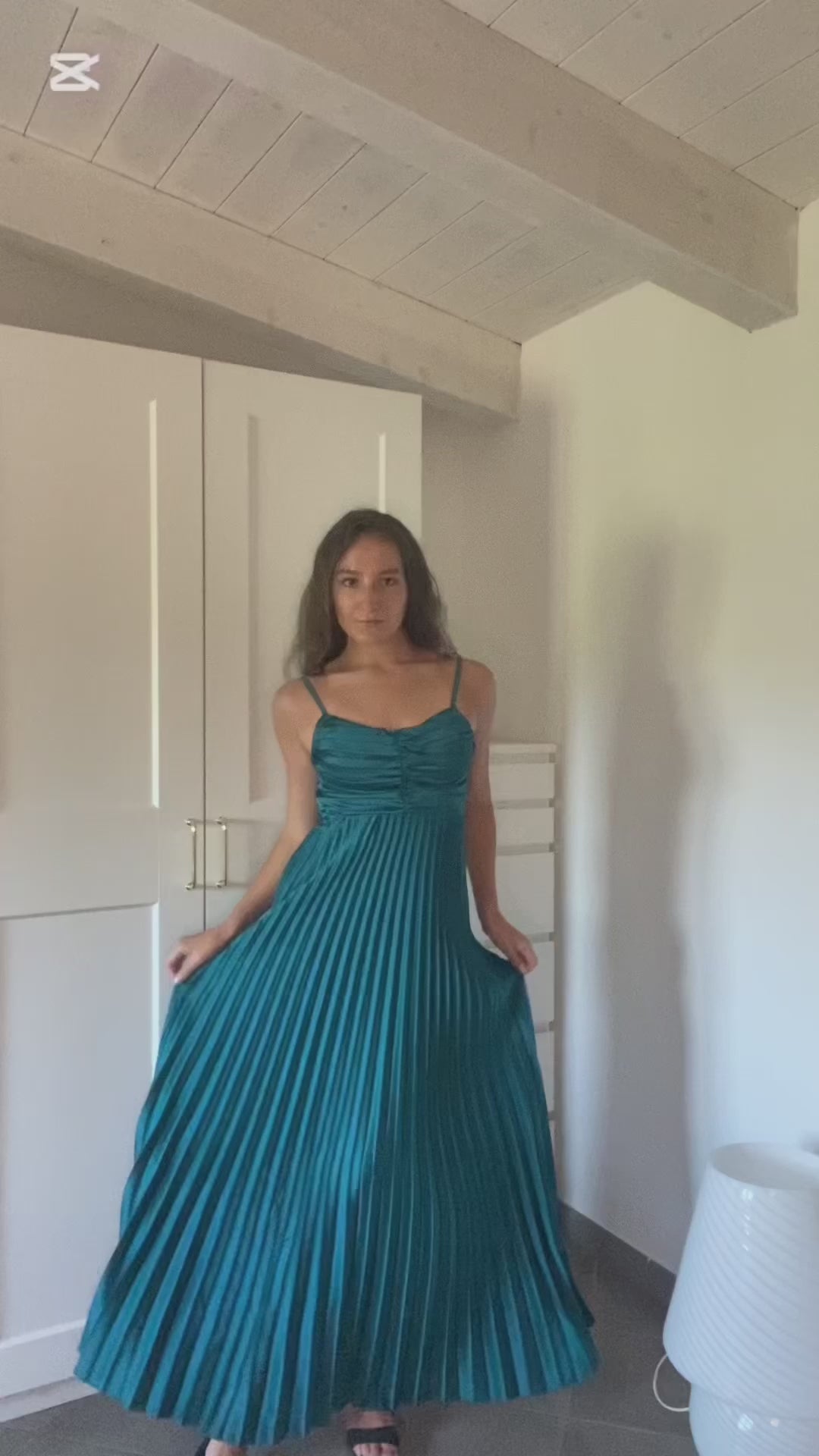 Donna con abito lungo blu a spalline sottili in ambiente domestico