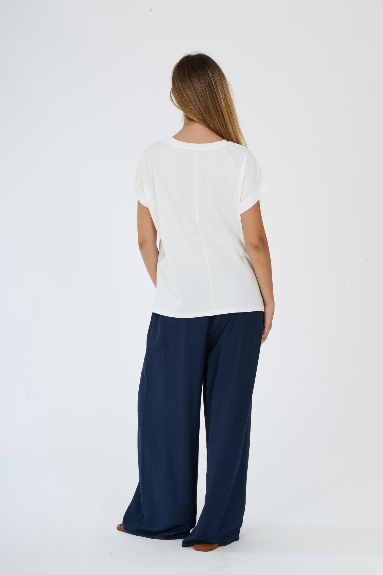 Outfit beige minimalista: t-shirt e pantaloni larghi su una persona