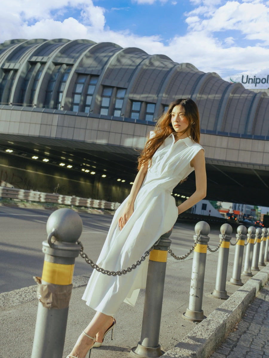 Abito bianco con dettagli sartoriali, silhouette fluida, perfetto per eventi all’aperto.