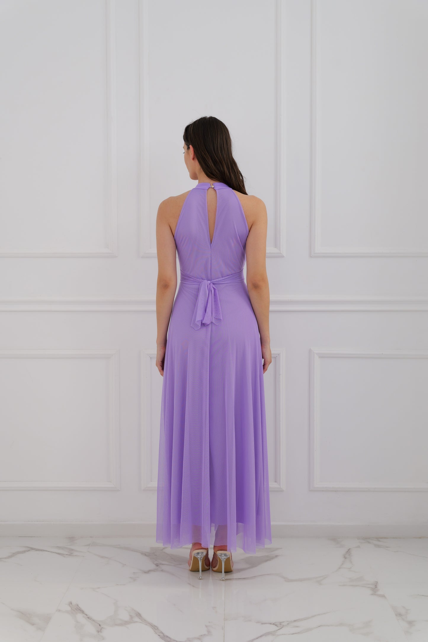 Abito lilla a halter, donna in posa elegante, pianta verde decorativa 