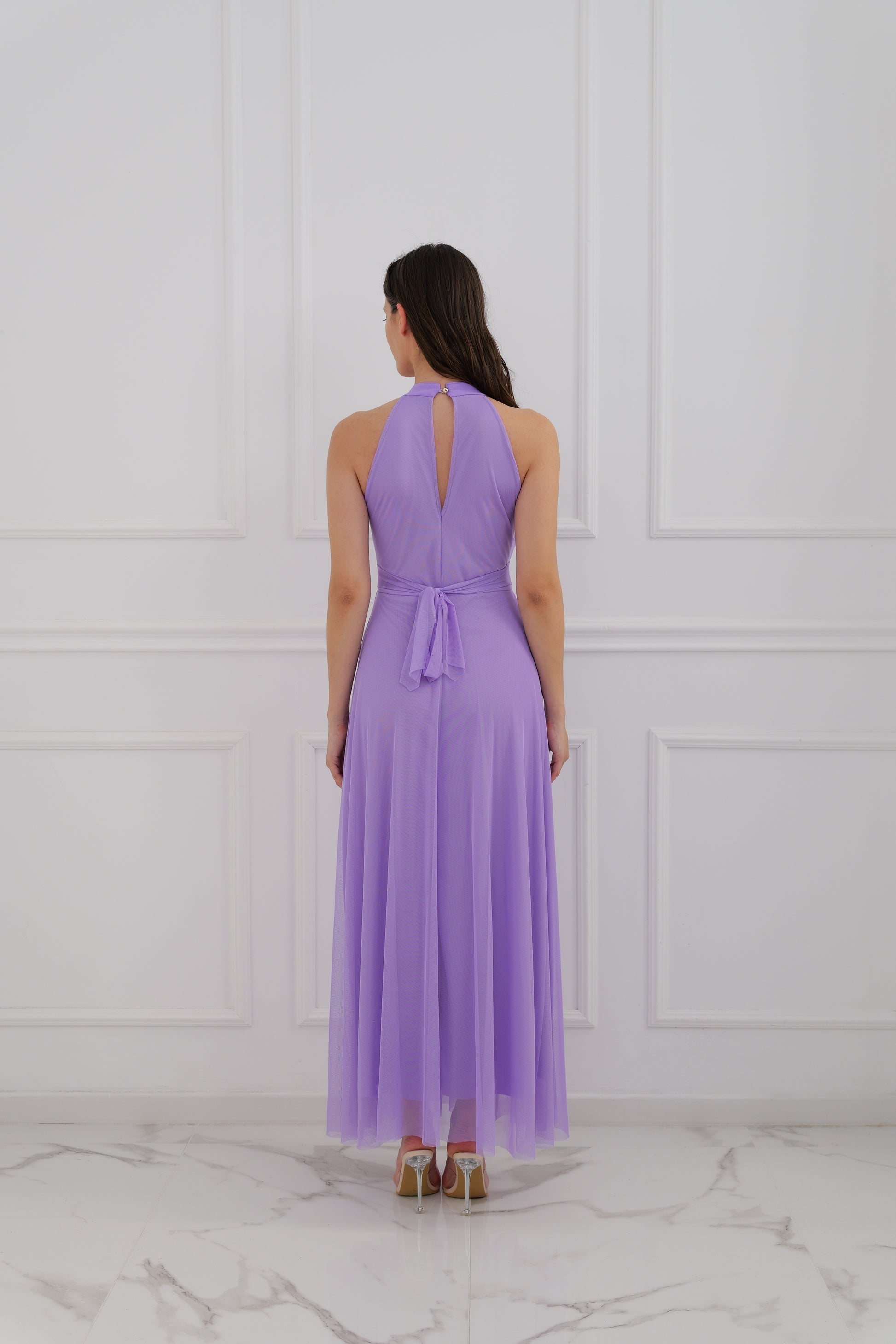 Abito lilla a halter, donna in posa elegante, pianta verde decorativa 