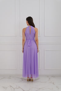 Abito lilla a halter, donna in posa elegante, pianta verde decorativa 