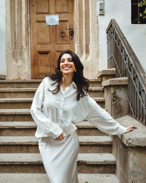 Una donna indossa una camicia di colore blu scuro intenso, con maniche lunghe e un leggero piegamento ai polsi,