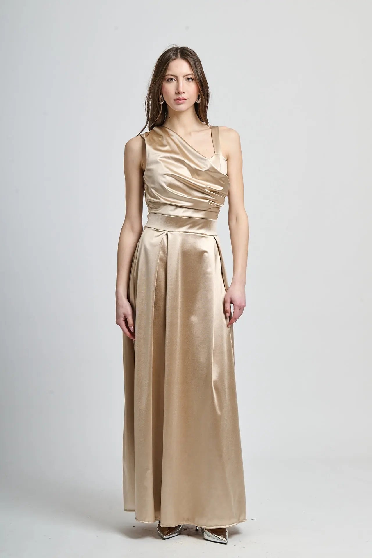 Abito beige in tessuto satinato, spalliera singola e drappeggiato sul busto.