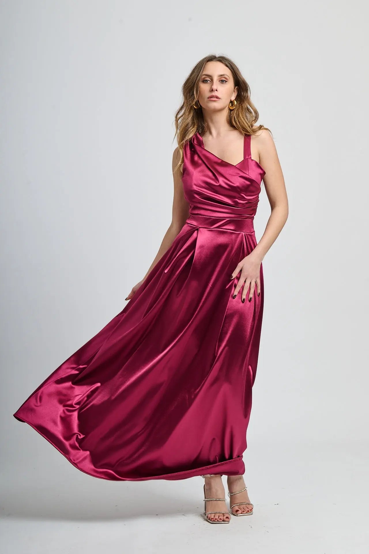 Abito bordo in tessuto satinato, spalliera singola e drappeggiato sul busto.