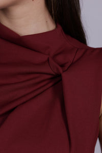 	Abito da donna bordeaux, senza maniche, midi, nodo sul petto, estetica elegante e intensa.
