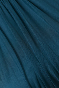 Abito da donna ottanio, collo alto a imbarcatura, gonna lunga, foulard in tulle, estetica elegante e contemporanea.