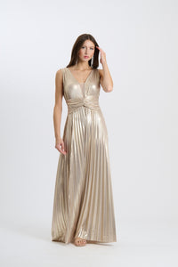 Abito da sera beige lungo, senza maniche, con plissé e scollatura a V, indossato da una donna in posa elegante.