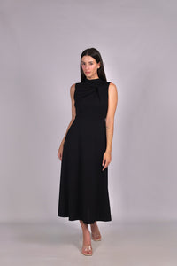 Abito nero da donna, senza maniche, lunghezza midi, dettaglio nodo sul petto, stile elegante e misterioso.