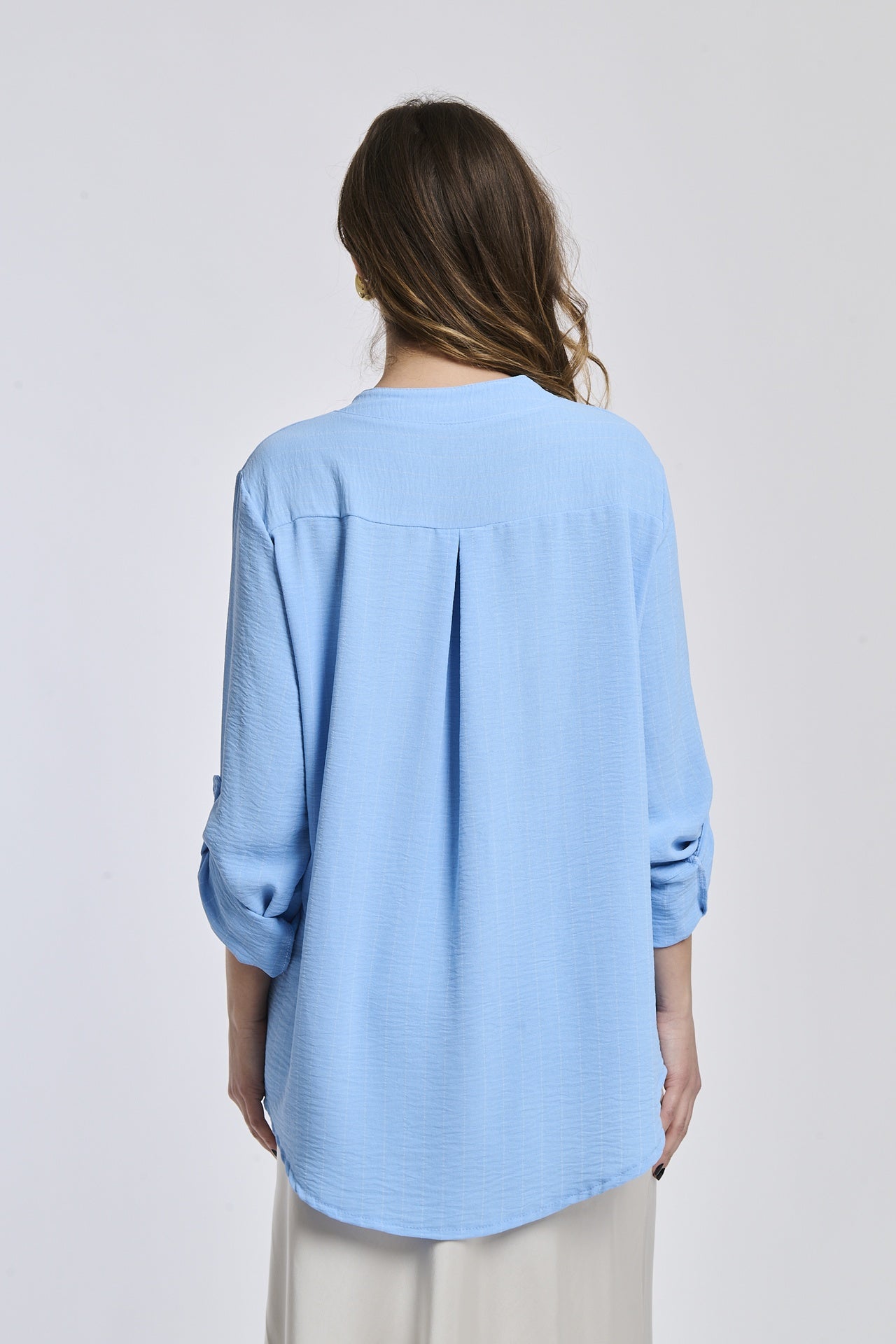 Camicia azzurra in tessuto leggero, due tasche anteriori, abbinata a gonna bianca