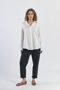 Camicia bianca in seta con colletto, abbinata a pantaloni beige.