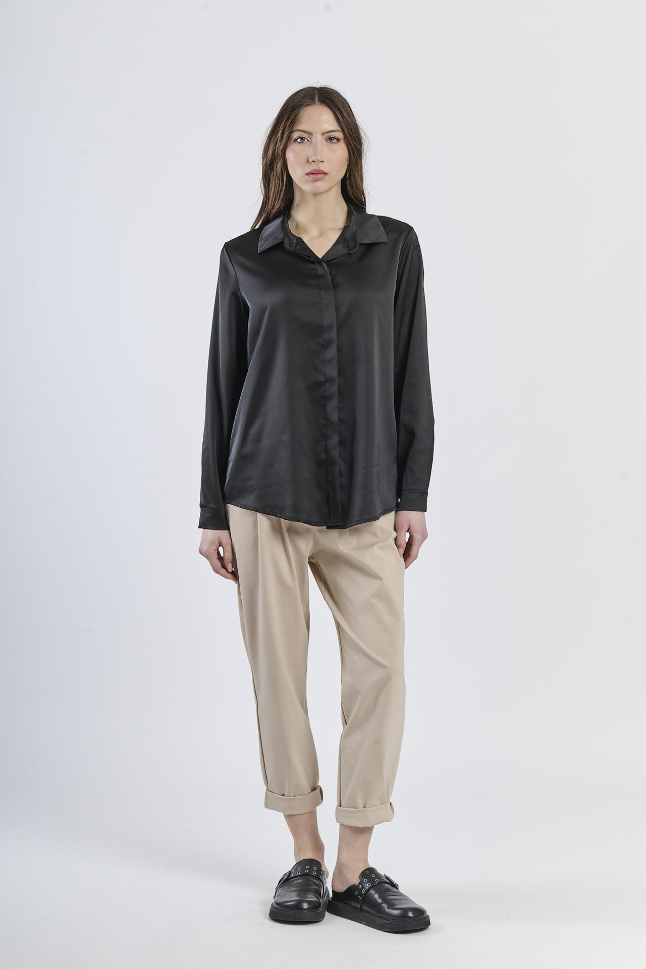 Camicia nera in seta con colletto, abbinata a pantaloni beige.