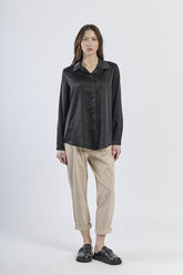 Camicia nera in seta con colletto, abbinata a pantaloni beige.