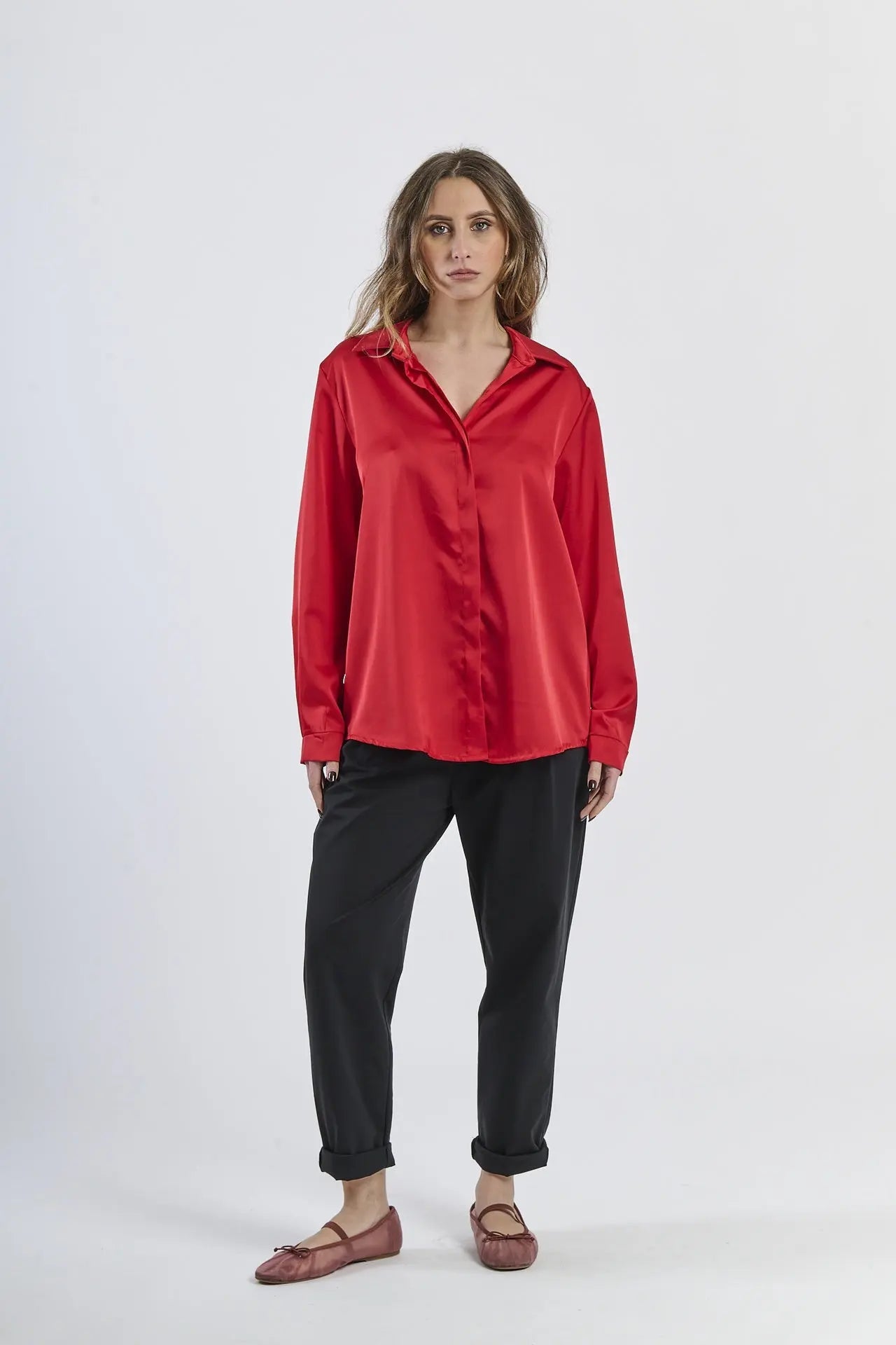 Camicia rossa in seta con colletto, abbinata a pantaloni beige.