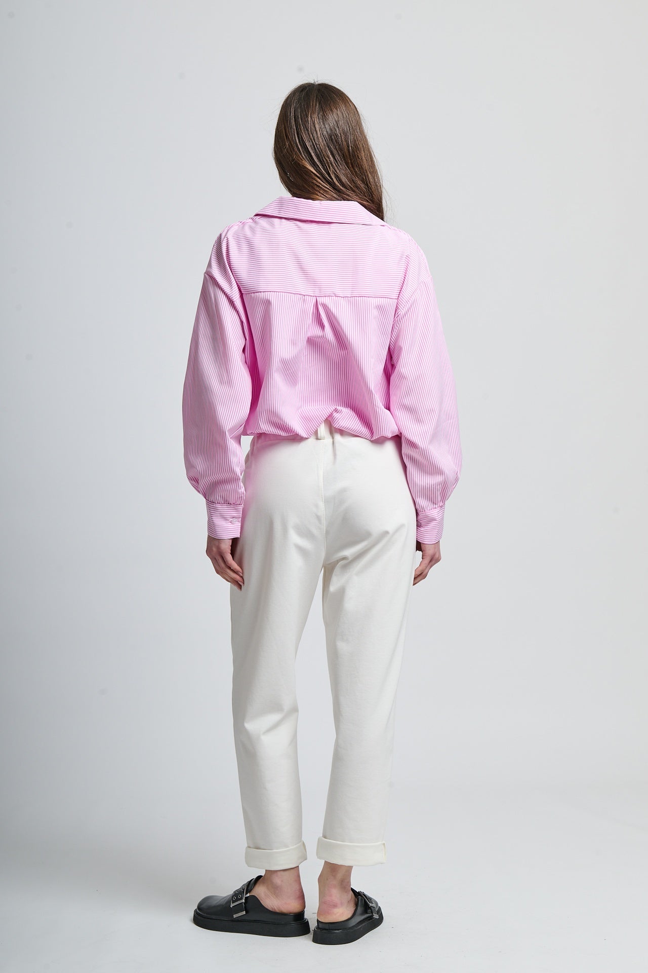 Combinazione camicia rosa a righe e pantaloni bianchi elegante