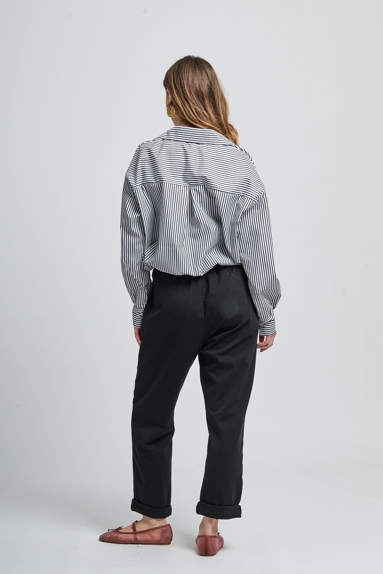 Combinazione camicia nero a righe e pantaloni bianchi elegante