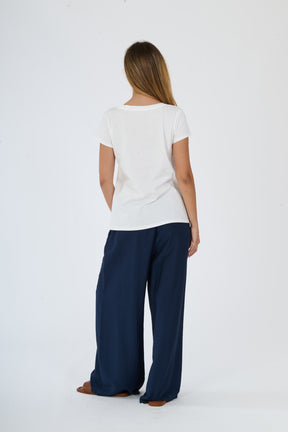 Completo bianco per l’estate: t-shirt e pantaloni larghi presentati da una ragazza