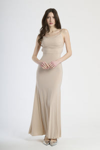 Donna con abito beige a spalline sottili, calore neutro e eleganza sobria.