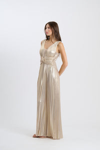 Donna con abito da sera beige, lungo, senza maniche, plissé e scollatura a V, in uno studio fotografico.
