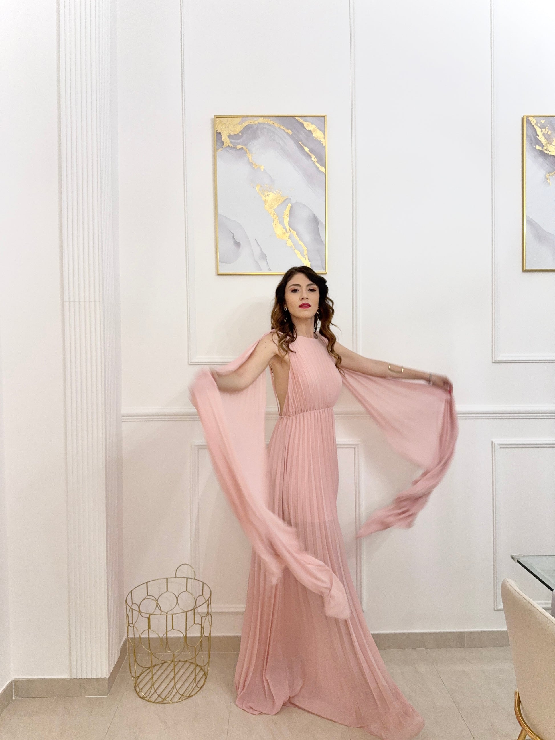 Donna con abito rosa plissé e mantelle, posa sul lago