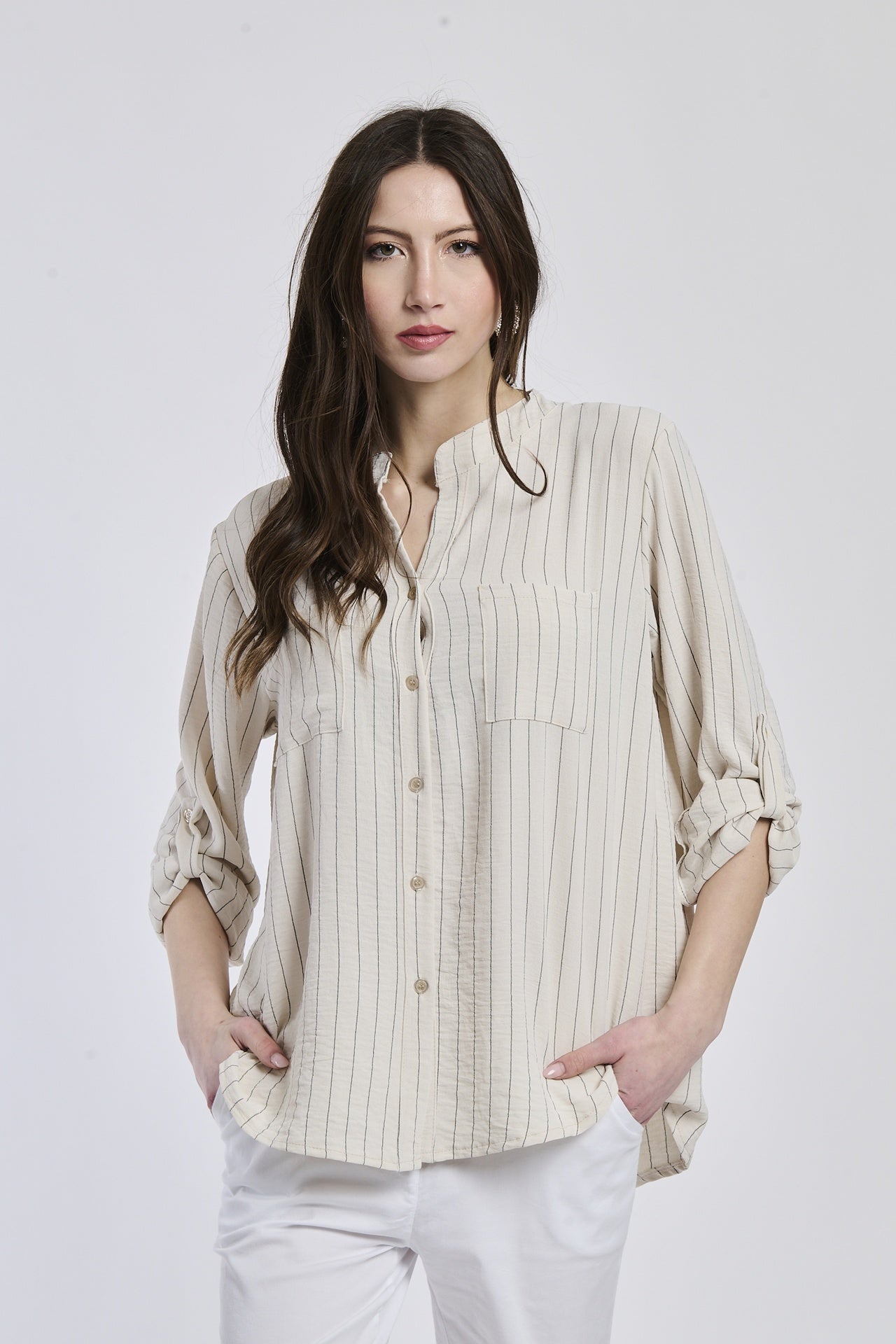 Donna con camicia beige a bottoni, collo rotondo, maniche lunghe rimboccate