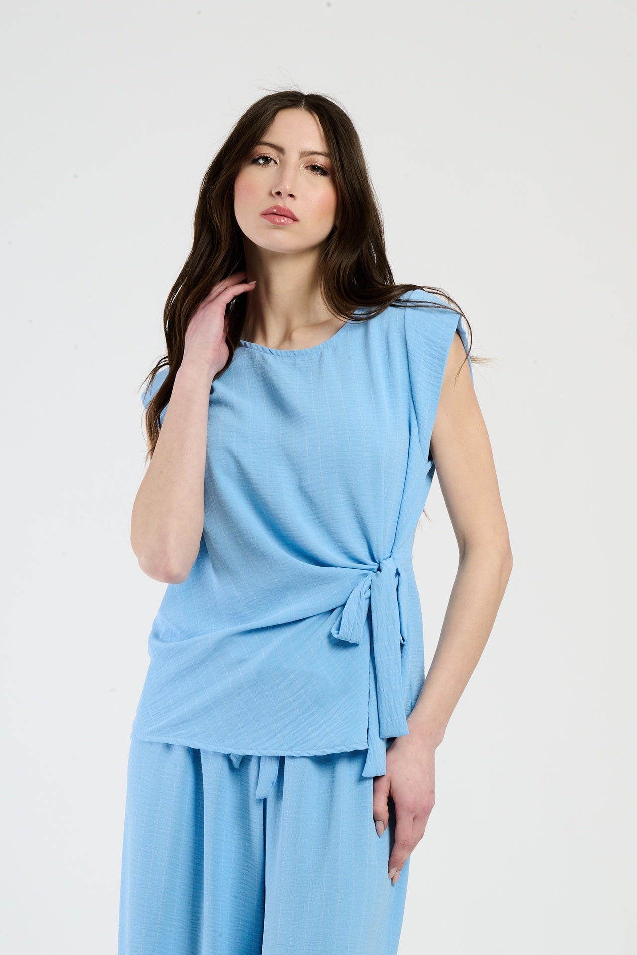 Donna con set azzurro: top senza spalline e pantaloni, design con nodo laterale.