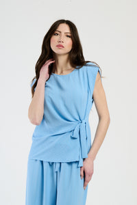 Donna con set azzurro: top senza spalline e pantaloni, design con nodo laterale.