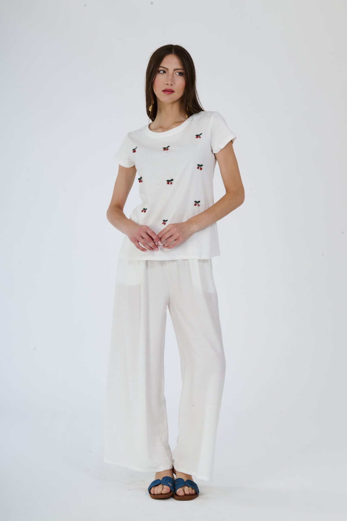 Donna con t-shirt bianca e pantaloni scuri larghi, sandali marroni